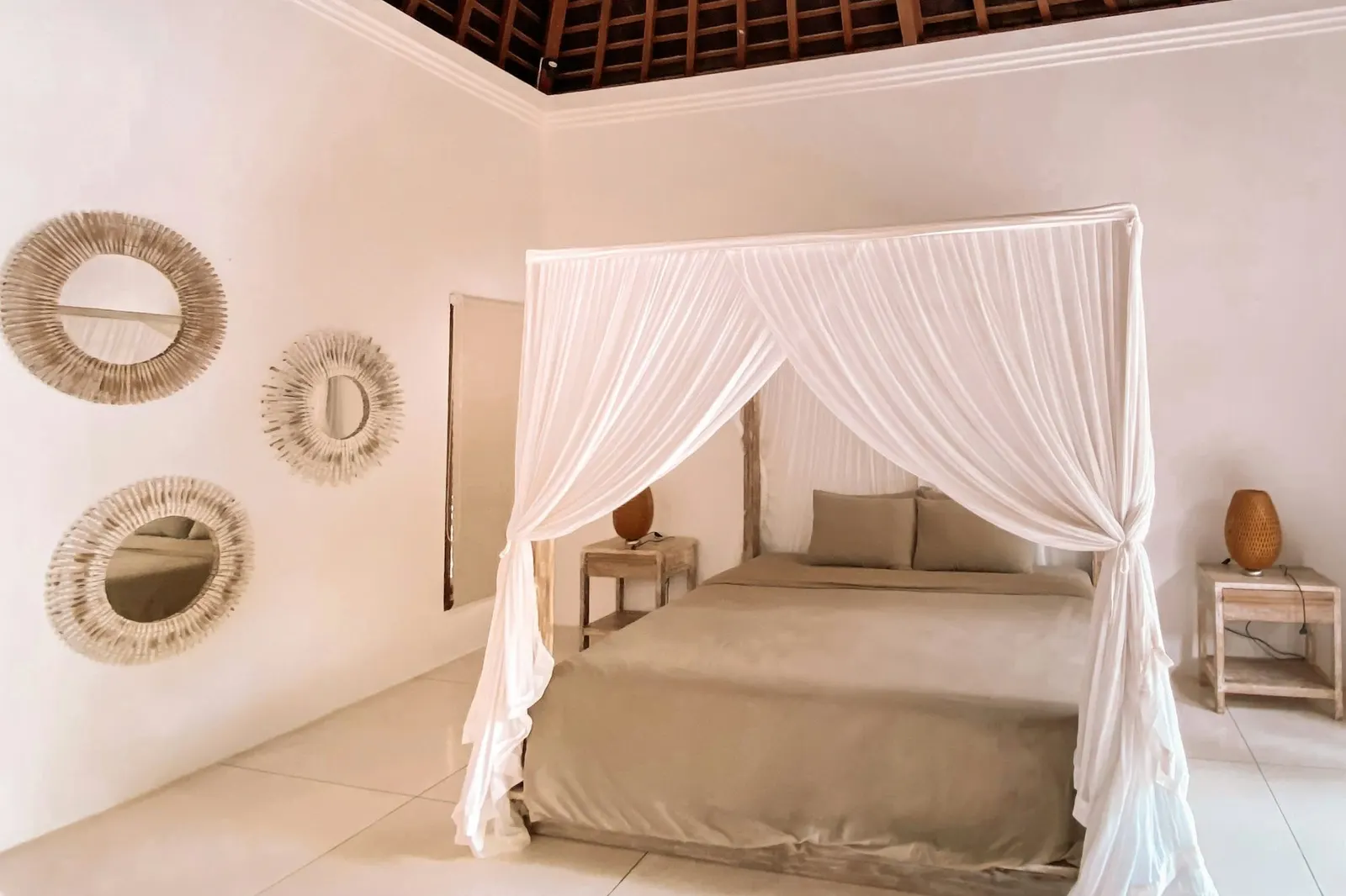 Serene bedroom with a white-draped four-poster bed beneath an exposed timber roof