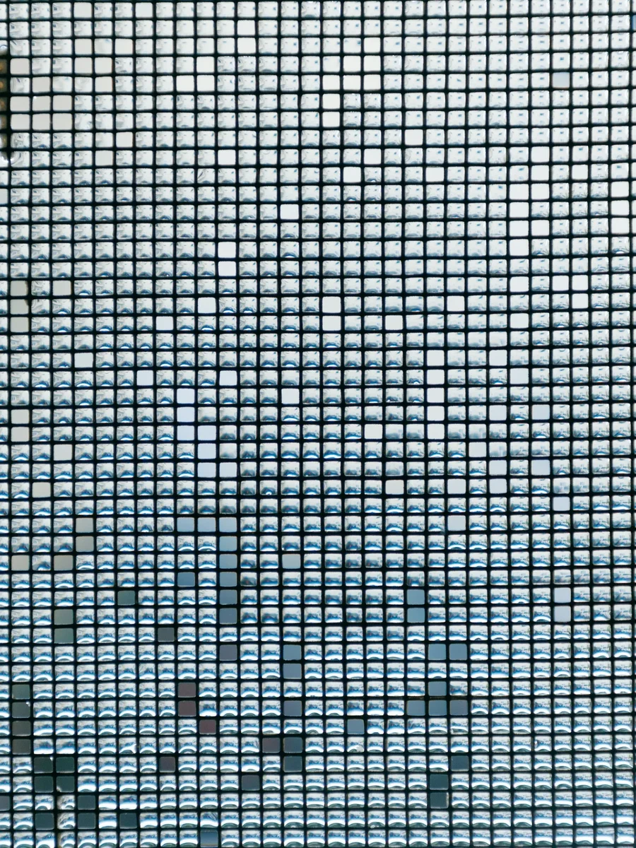 Close-up of a woven window insect mesh with rain droplets caught in its square openings