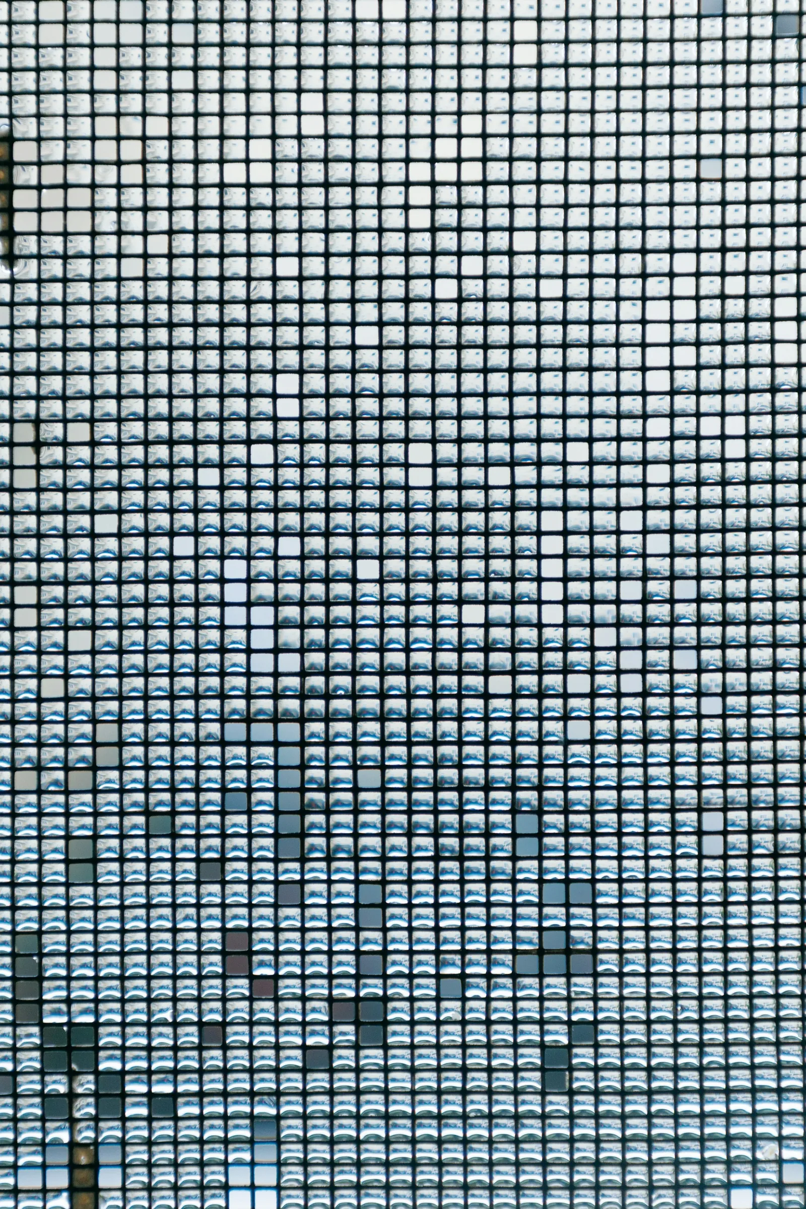 Close-up of a woven window insect mesh with rain droplets caught in its square openings