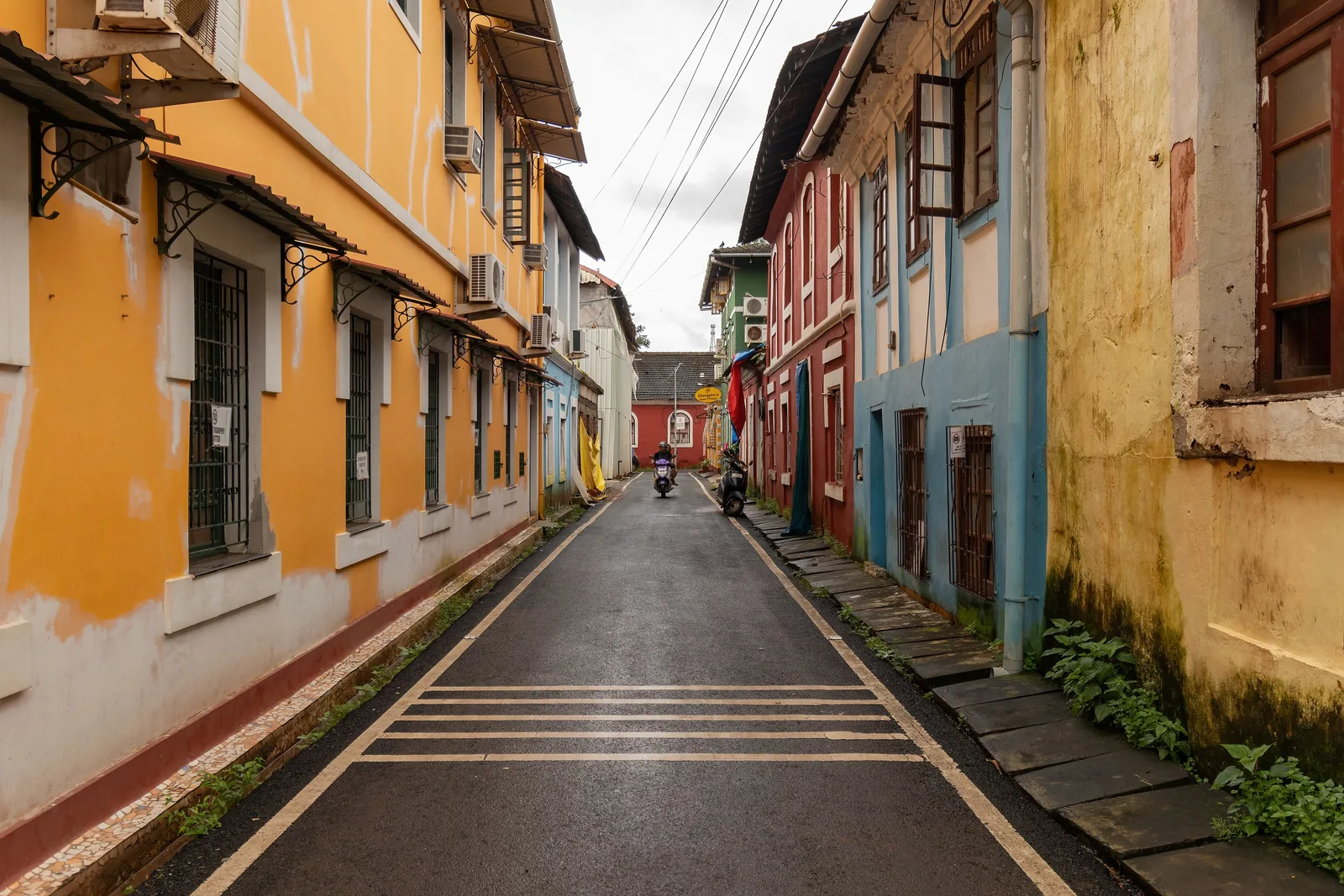 A narrow Fontainhas lane in Panjim lined with ochre, blue and red old houses after rain