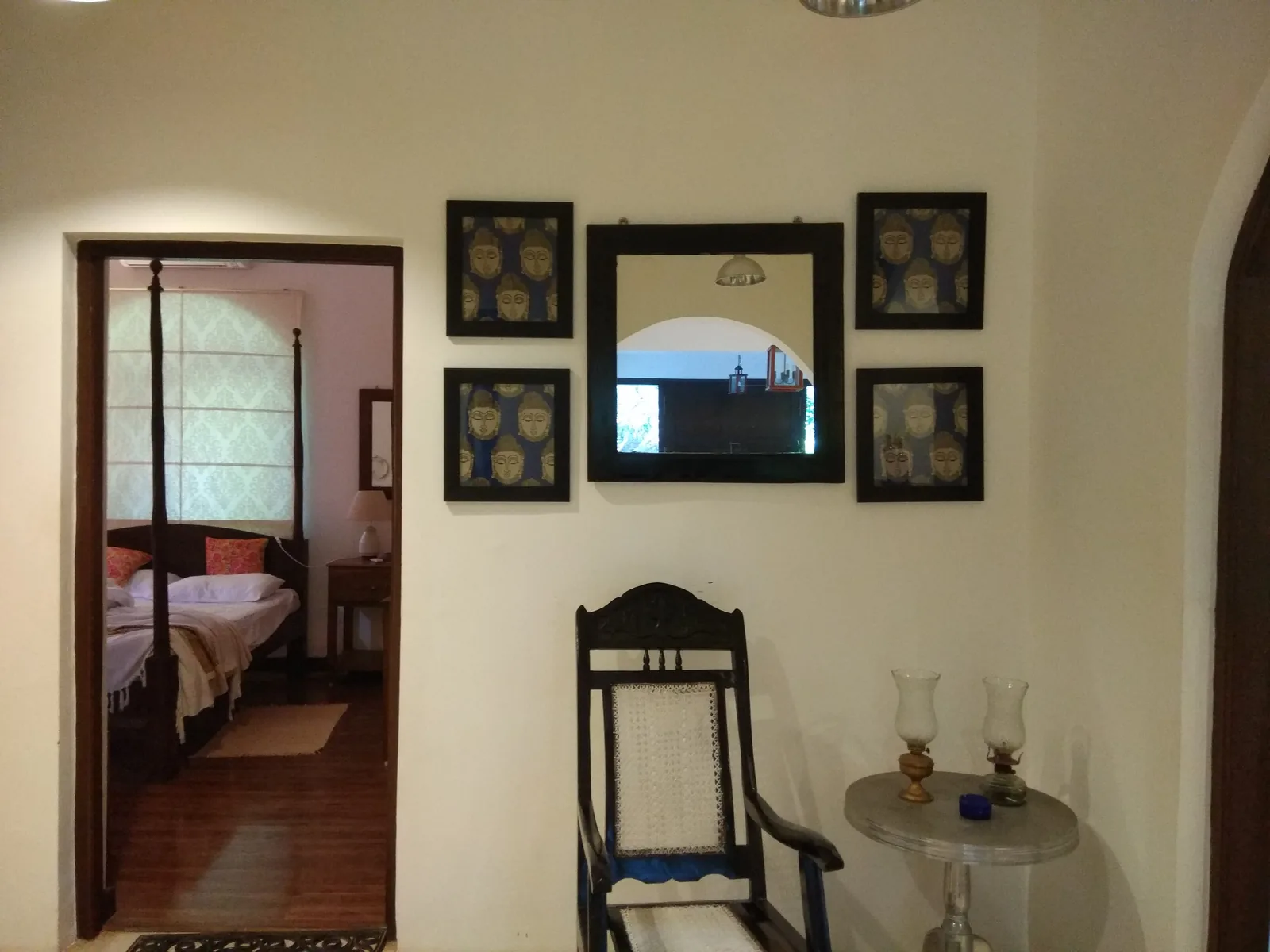 Inside a Goan house: a hall with a cane planter's chair and a doorway opening onto a four-poster bedroom