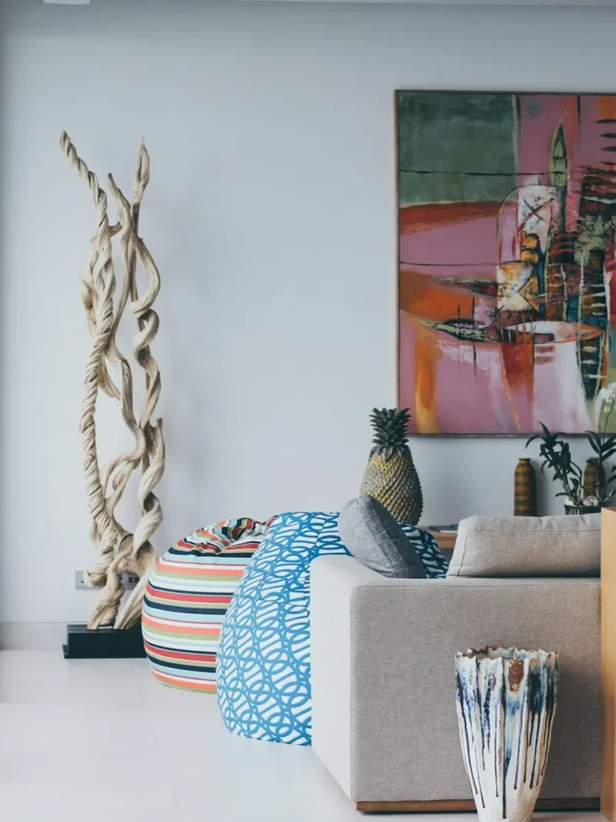 Bright staged living room with a pale sofa, driftwood sculpture and a large abstract painting