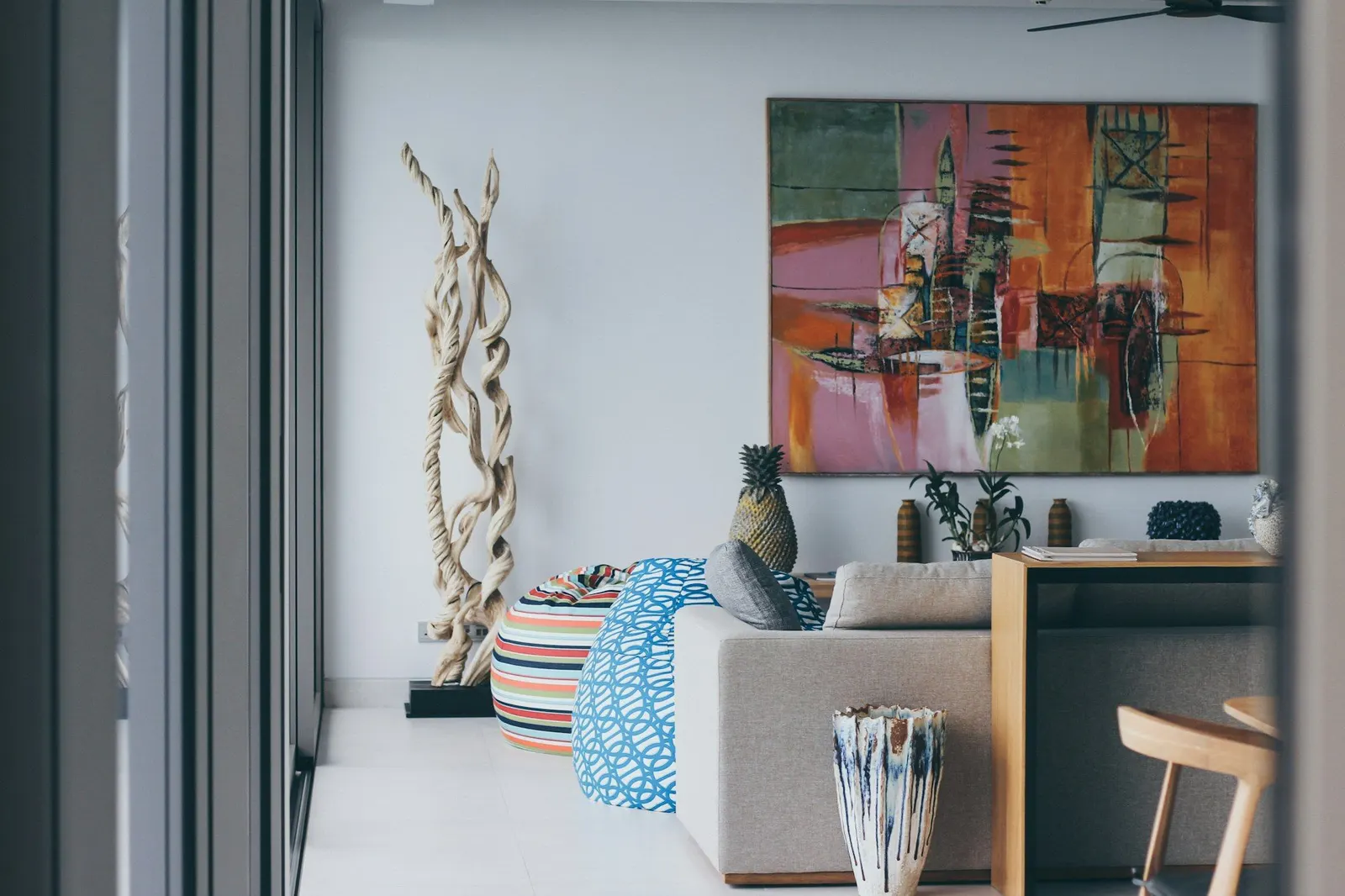 Bright staged living room with a pale sofa, driftwood sculpture and a large abstract painting