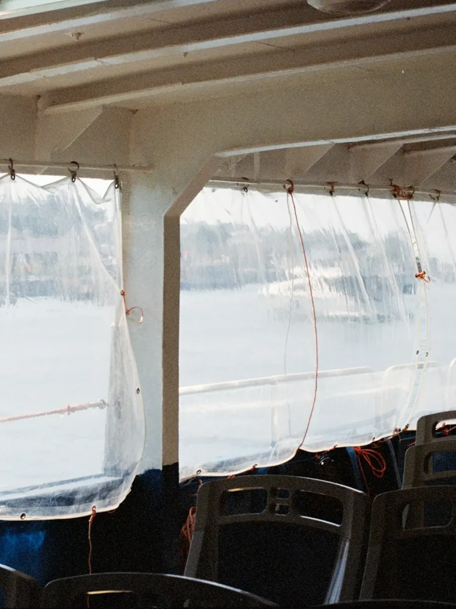 Clear plastic roll-down curtains tied along the open side of a covered deck above water