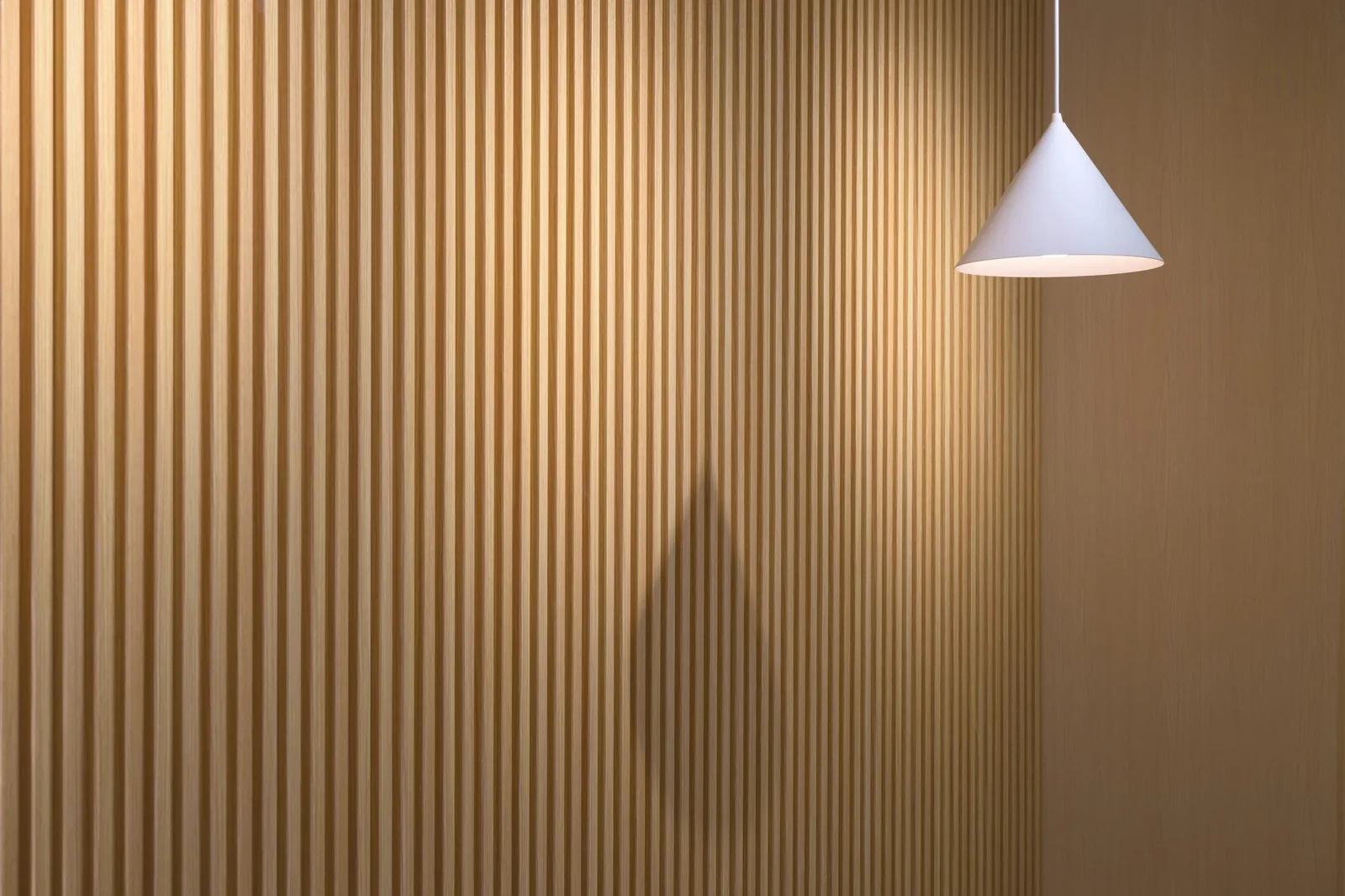 Light oak-effect slatted wall panels with a white cone pendant light hanging alongside