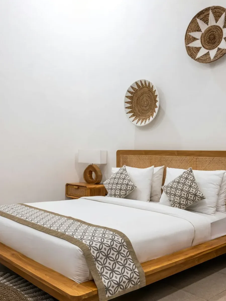 Neatly made guest bed with a rattan headboard, rattan bedside tables and woven wall baskets