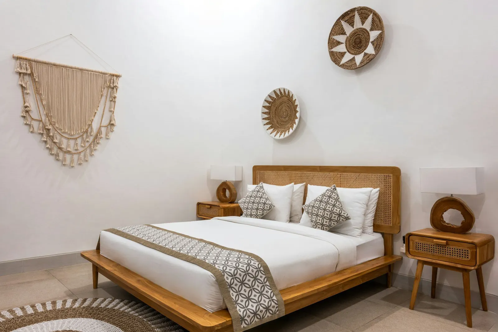 Neatly made guest bed with a rattan headboard, rattan bedside tables and woven wall baskets