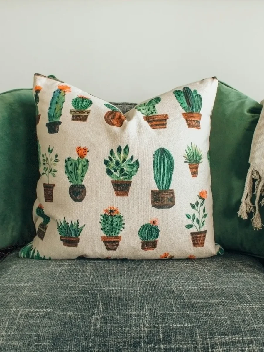 Green velvet and cactus-print cushions with a fringed linen throw on a grey textured sofa