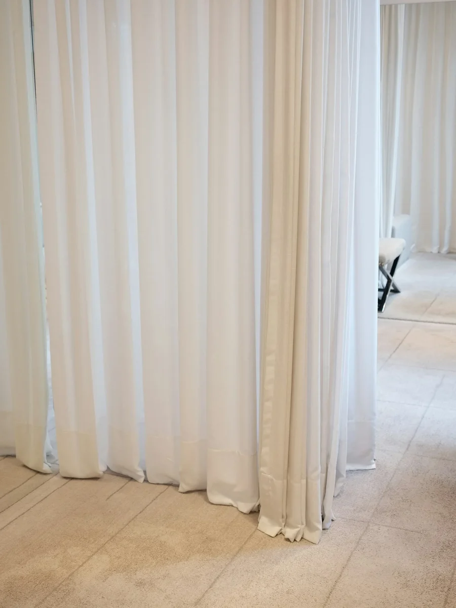 Full-height white sheer curtains hung from the ceiling to screen off part of a room