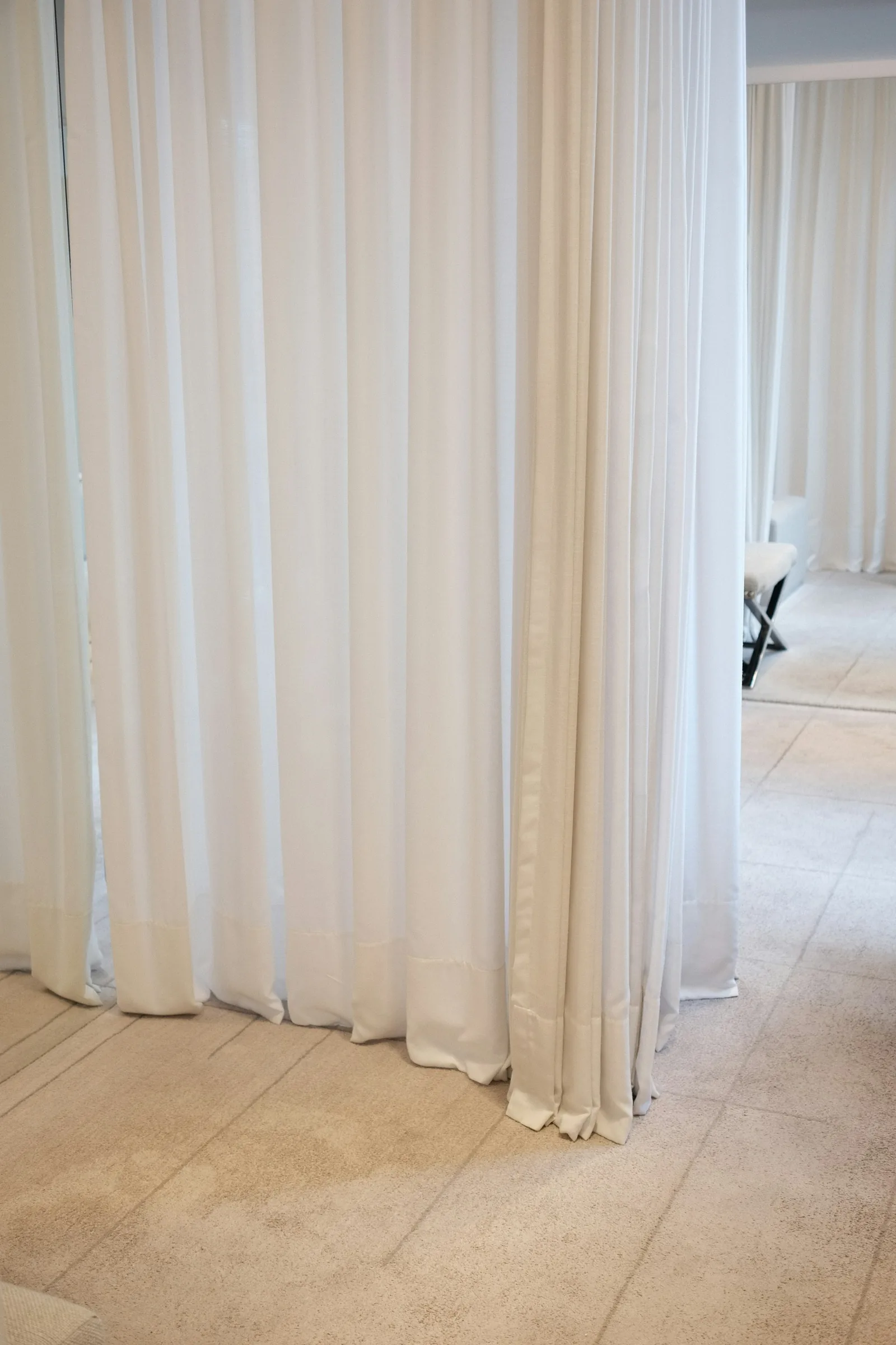 Full-height white sheer curtains hung from the ceiling to screen off part of a room