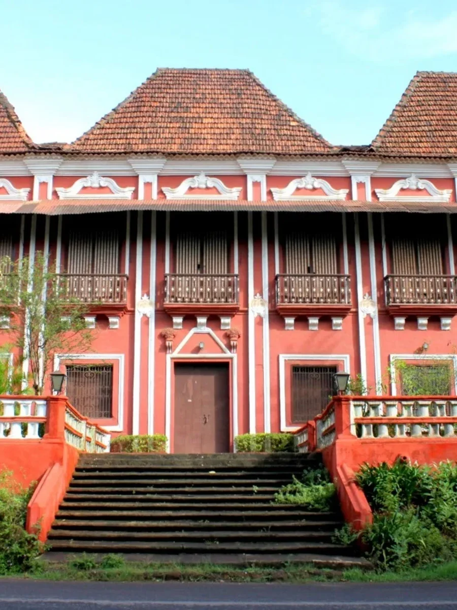 A red-and-white Goan-Portuguese mansion in Margao with three pyramidal gables, balconies and a broad front stair