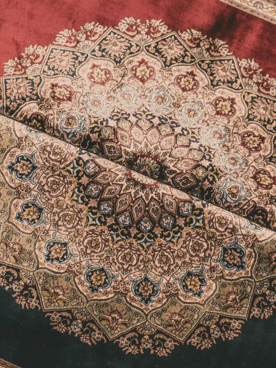 Two folded silk-pile carpets with fine medallion patterns on red and blue-grey grounds