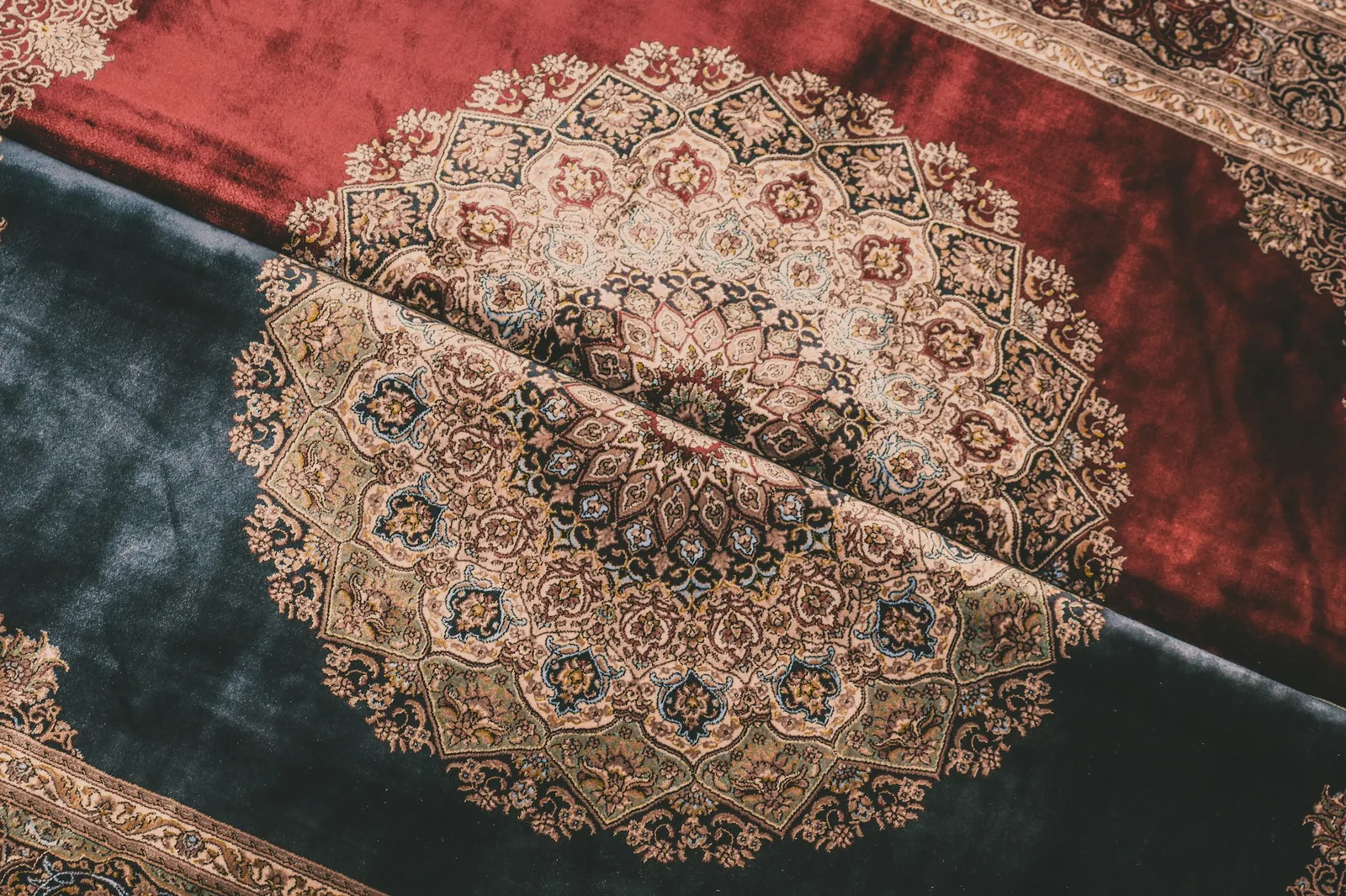 Two folded silk-pile carpets with fine medallion patterns on red and blue-grey grounds