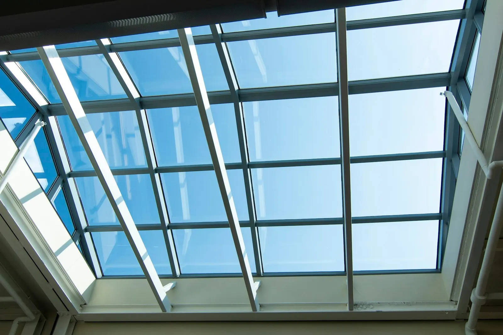Large glazed skylight with white frames looking up at a clear blue sky
