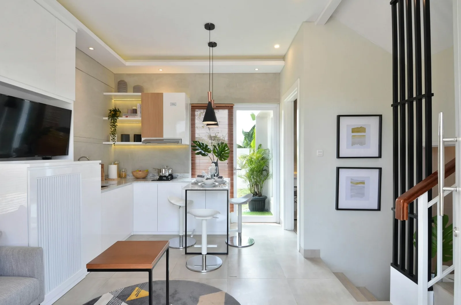 A compact open-plan townhouse living area leading to a small white kitchen and a garden door