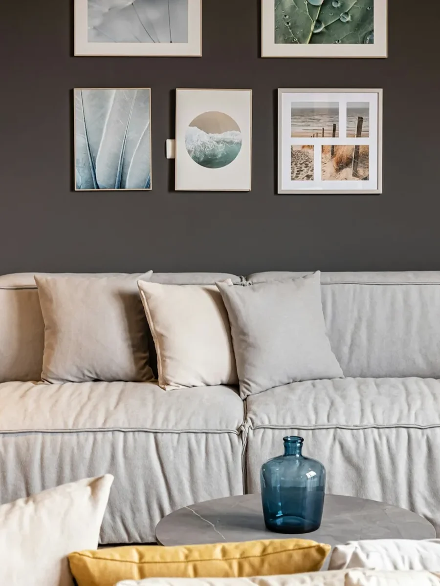 Loose-covered grey fabric sofa with cushions against a dark charcoal wall