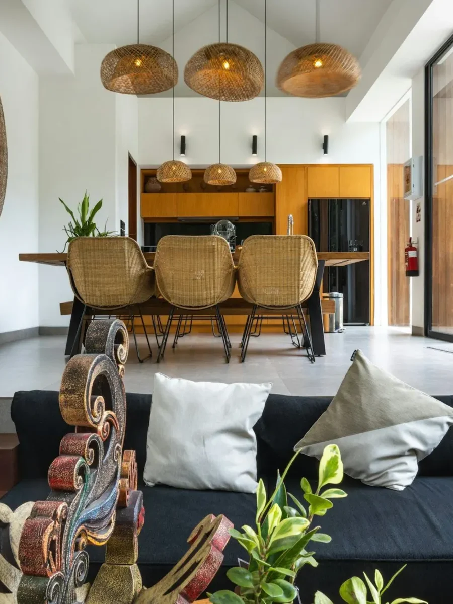 Open-plan living and dining space with rattan chairs, woven pendant lights and plants
