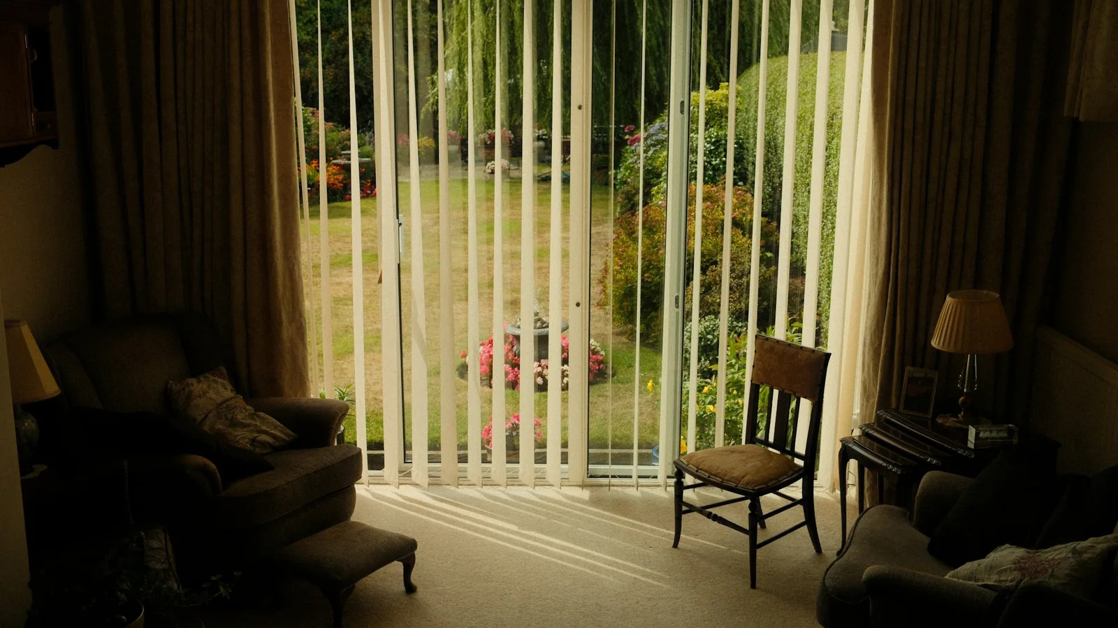 Cream vertical blinds drawn back from a wide garden door in a traditionally furnished sitting room