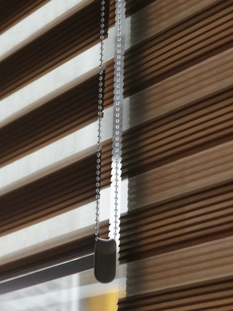 Brown and sheer striped zebra blind with a beaded chain control at a window