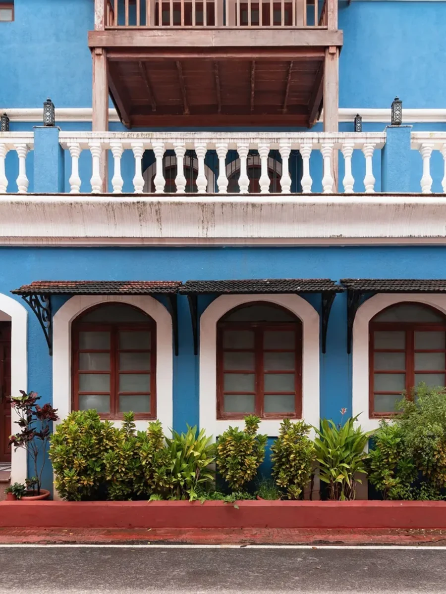 A bright blue Fontainhas house in Panaji with white balustrade, arched windows and a yellow neighbour
