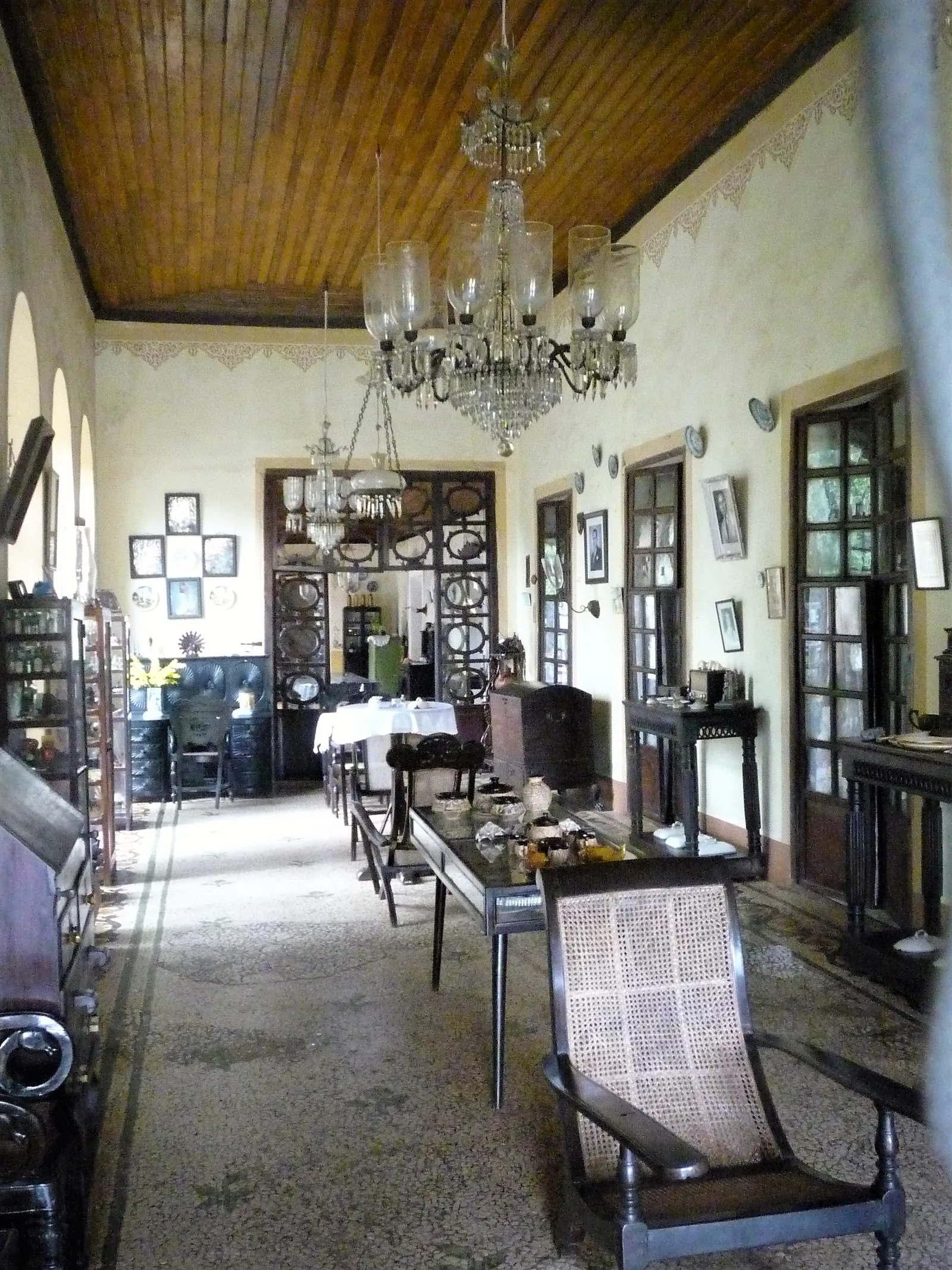 A long hall in an old Chandor mansion under a dark wooden plank ceiling with crystal chandeliers