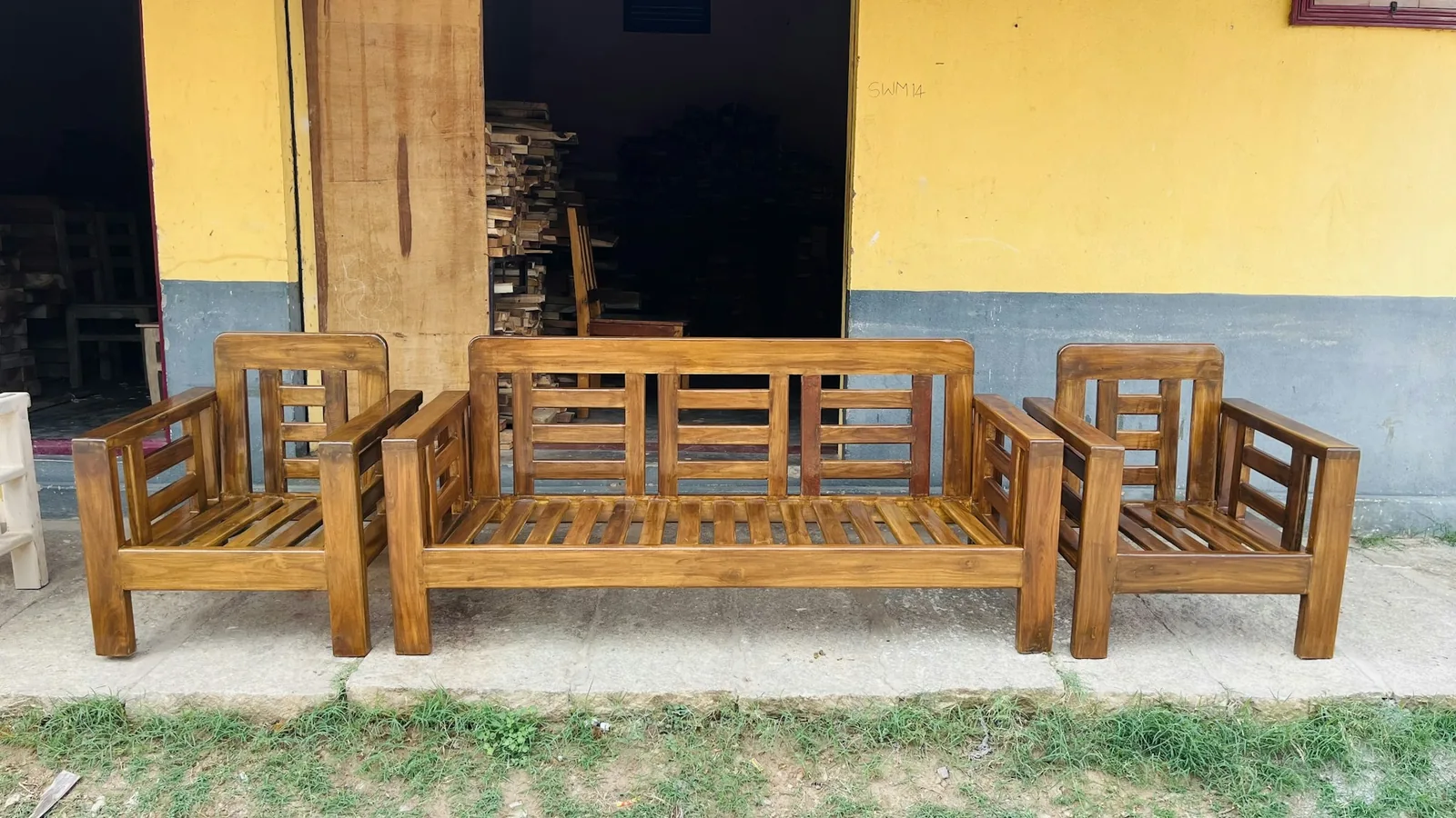 Solid wood slatted sofa set, a three-seater and two armchairs, outside a timber workshop