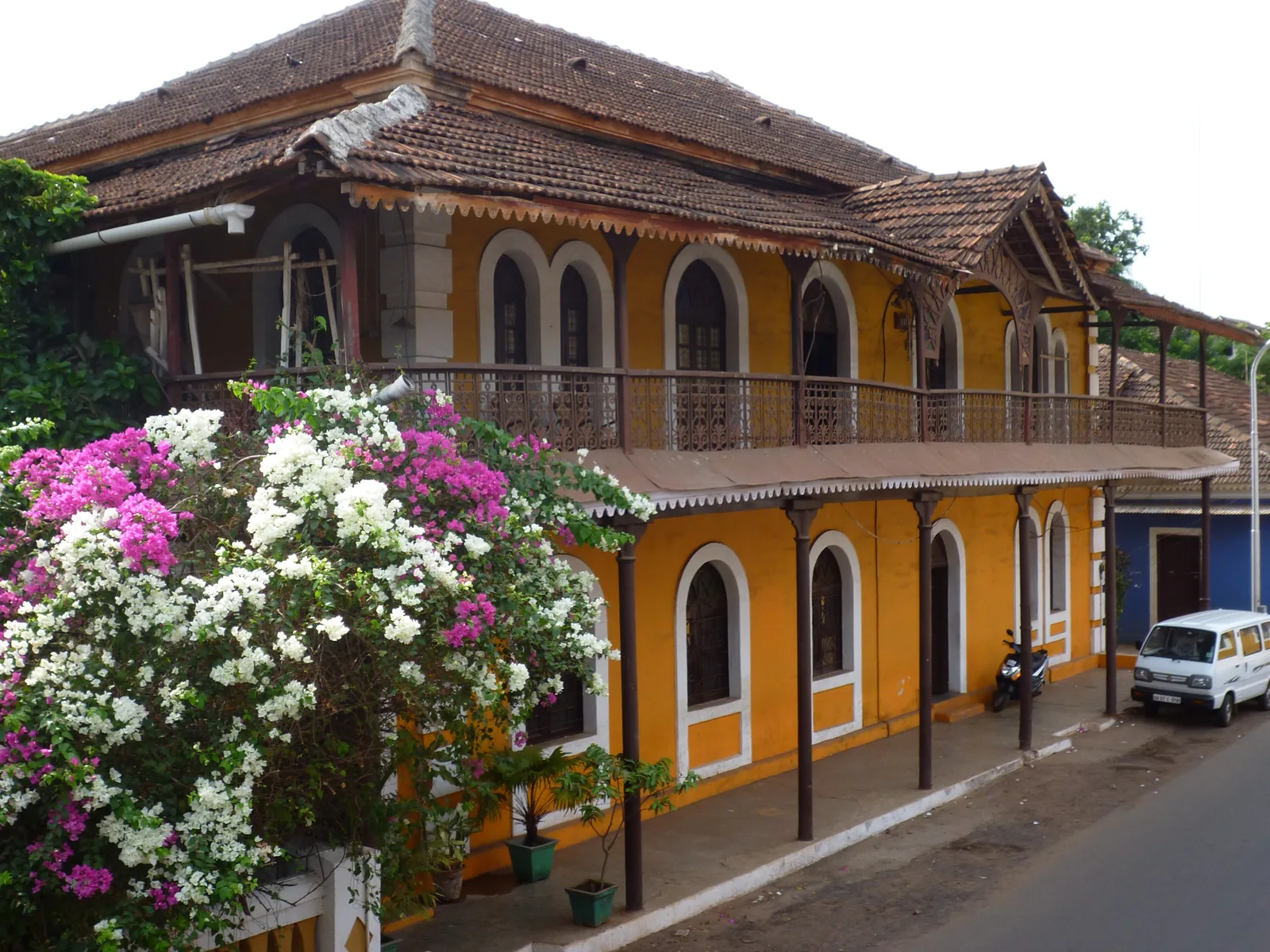 Ochre-yellow two-storey house in Fontainhas, Panjim, with a long iron balcony and bougainvillea in flower