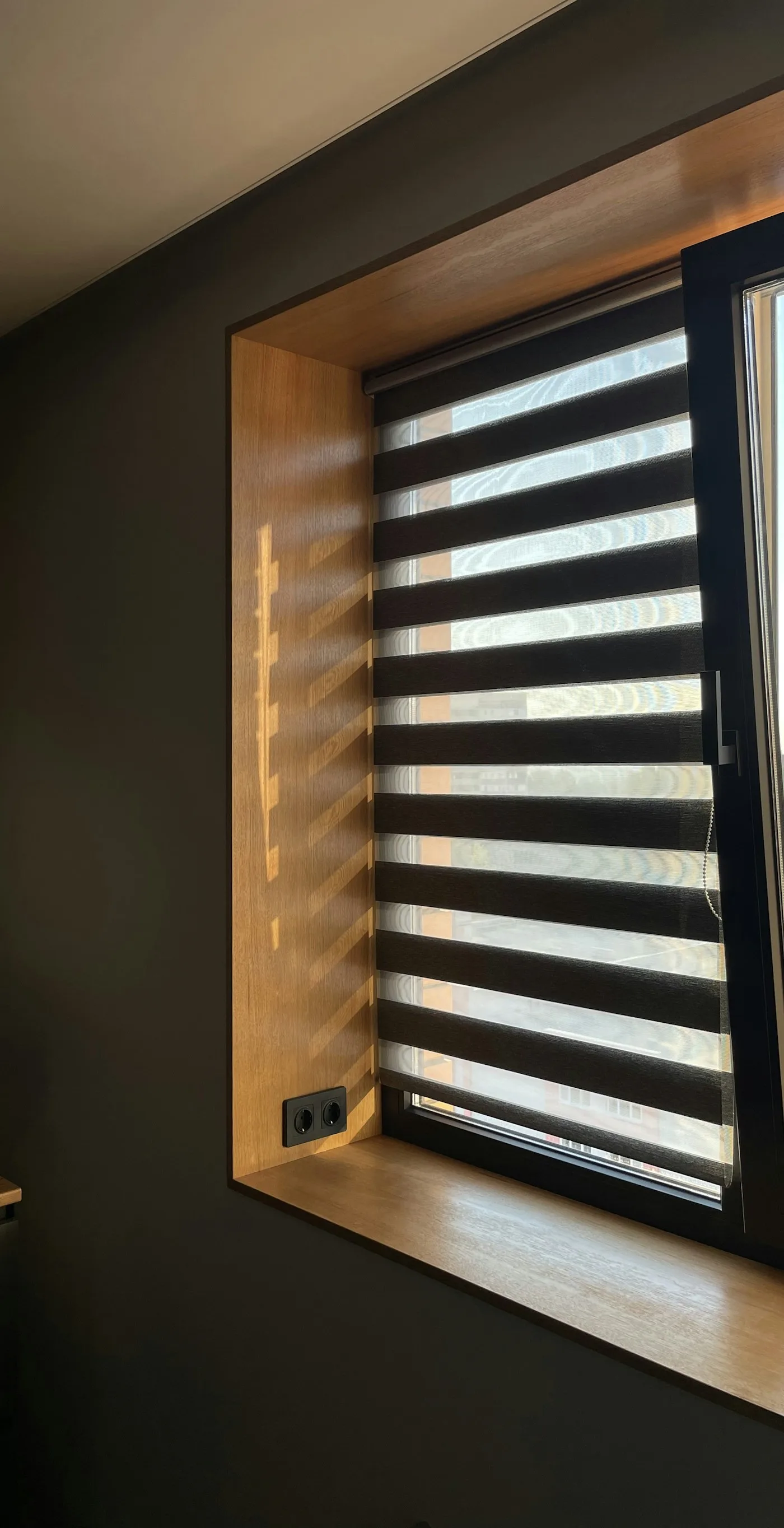 A day-and-night zebra blind with alternating sheer and solid bands in a timber-lined window