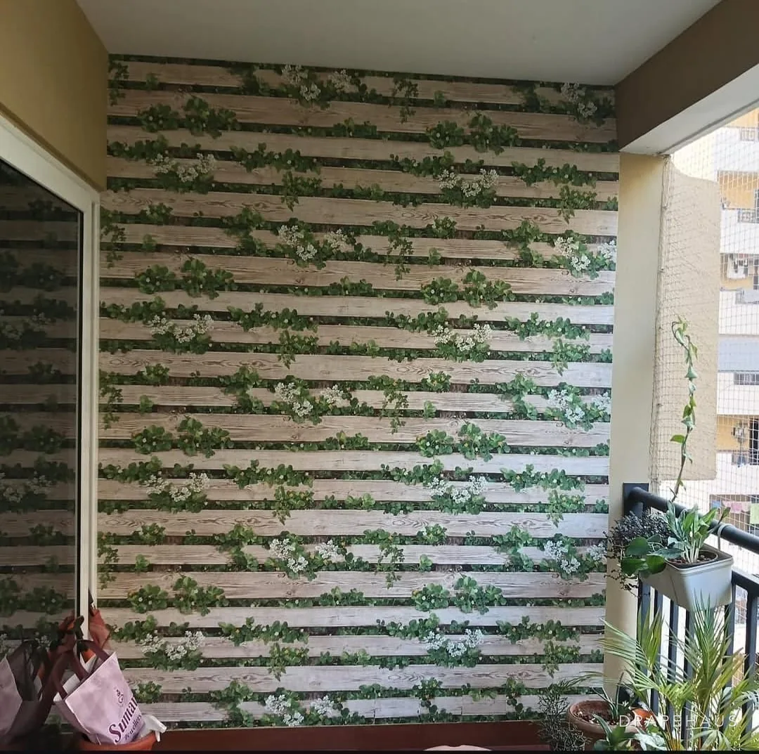 Trompe-l'oeil timber and foliage wallpaper on an apartment balcony wall with potted plants alongside
