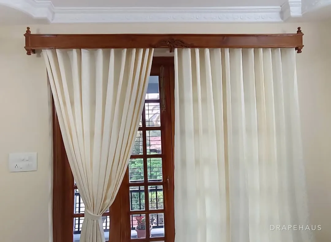 Ivory sheers tied back from timber French doors beneath a carved hardwood pelmet