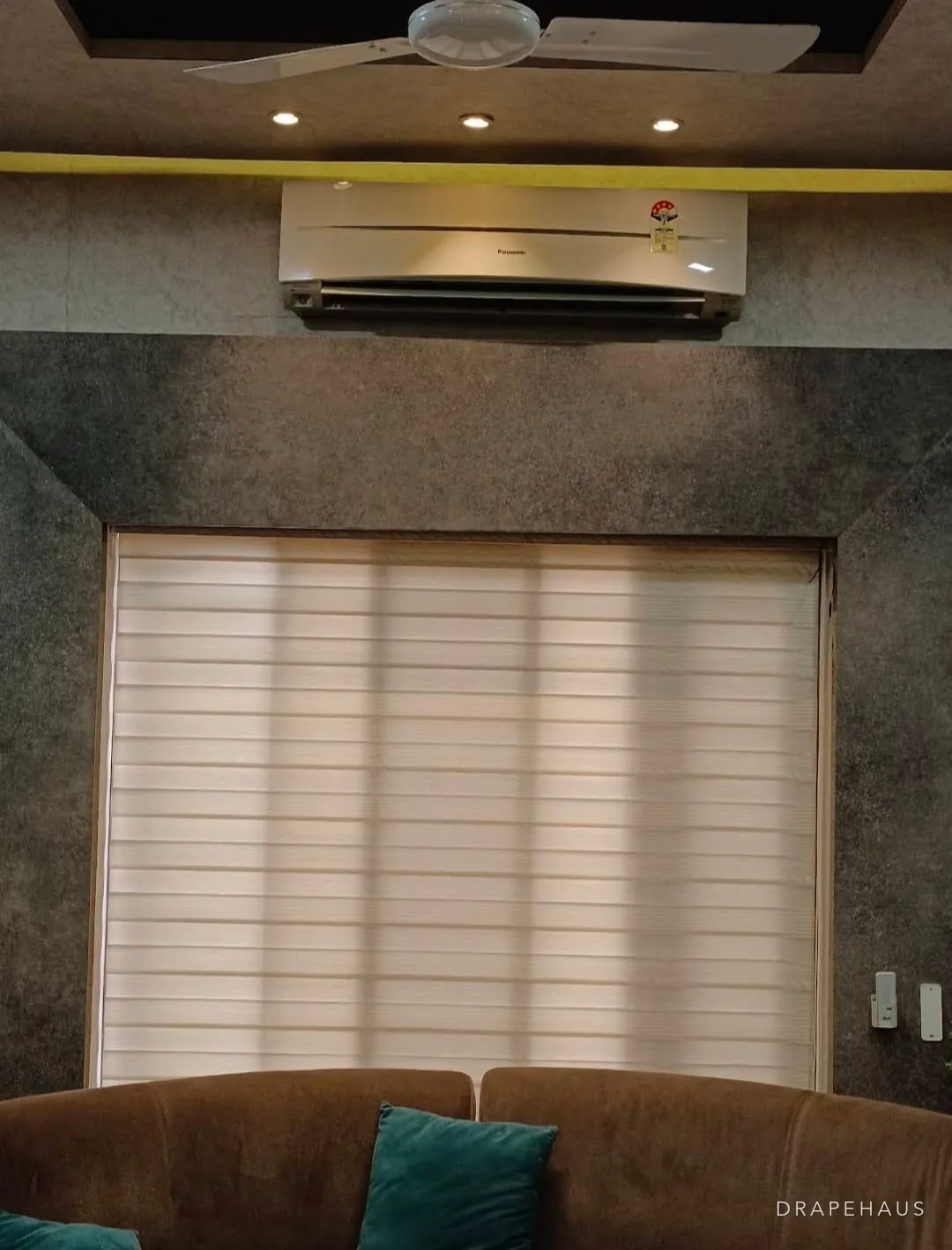 A zebra blind fitted across a living-room window, part-open to show its bands