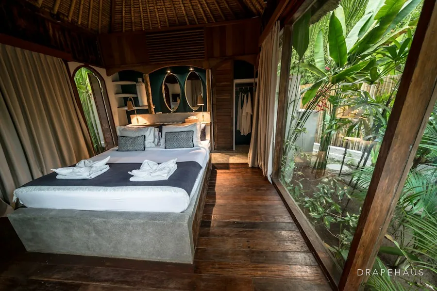 A guest bedroom made up for the season, opening onto a shaded veranda