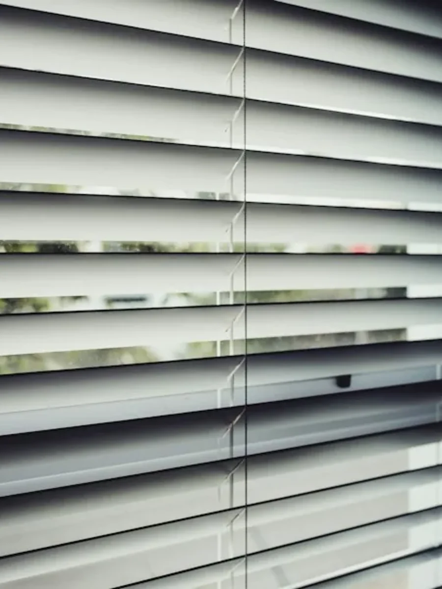 Dark slatted blinds on a tall window, lowered by motor