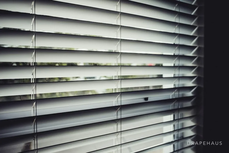 Dark slatted blinds on a tall window, lowered by motor