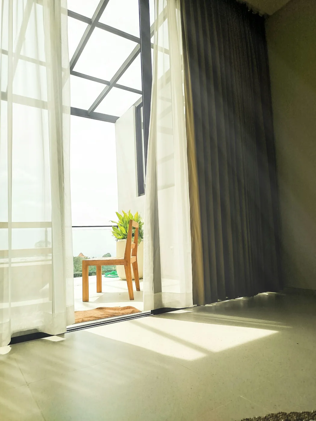 A covered Goan balcony with outdoor seating and shade on the open side