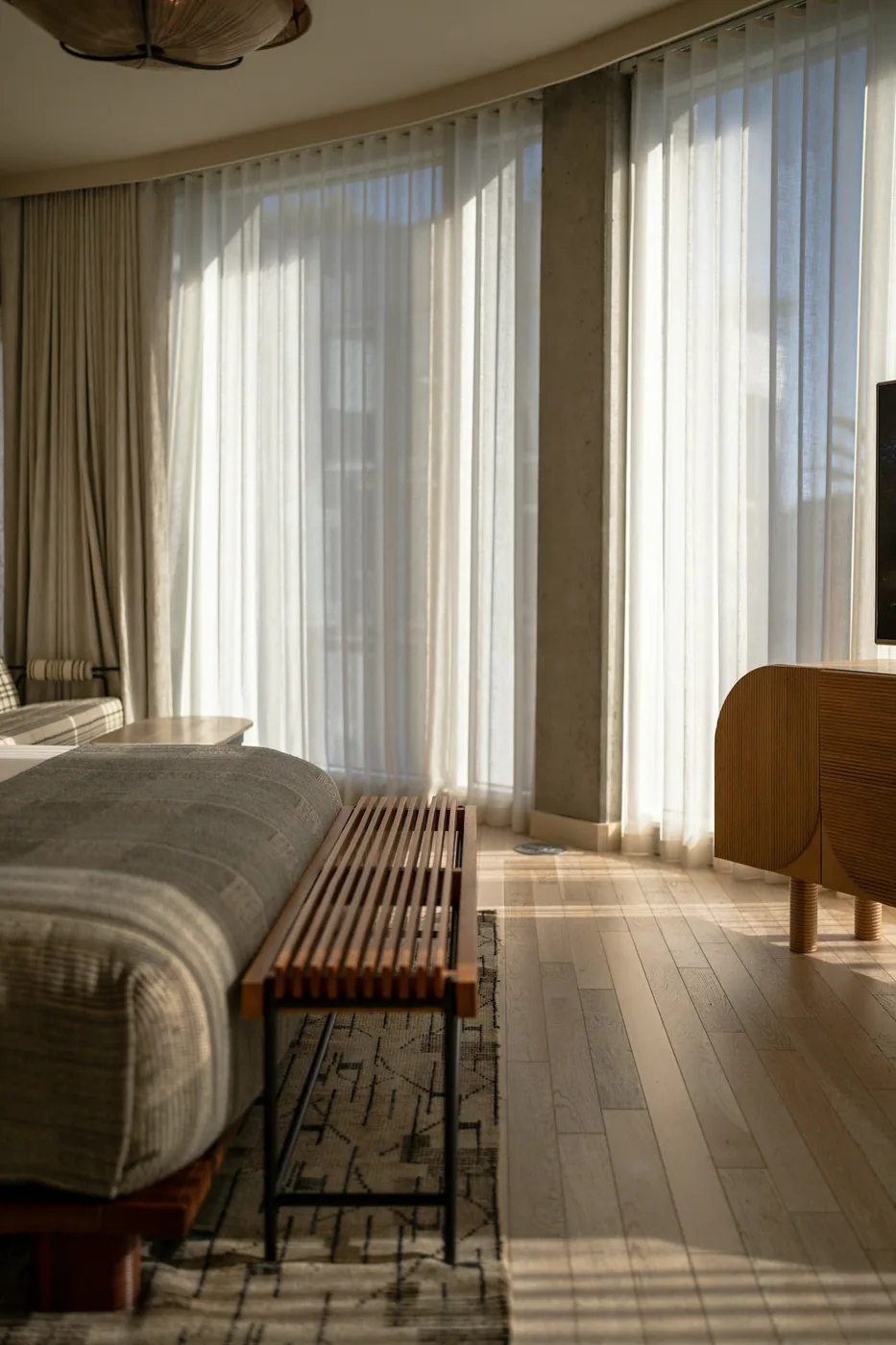 A calm bedroom with curtains drawn across the window beside a made bed