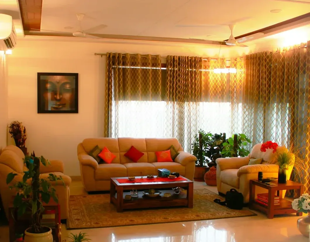 A spacious Goan hall with tall windows, curtains and a large sofa arranged for family gatherings