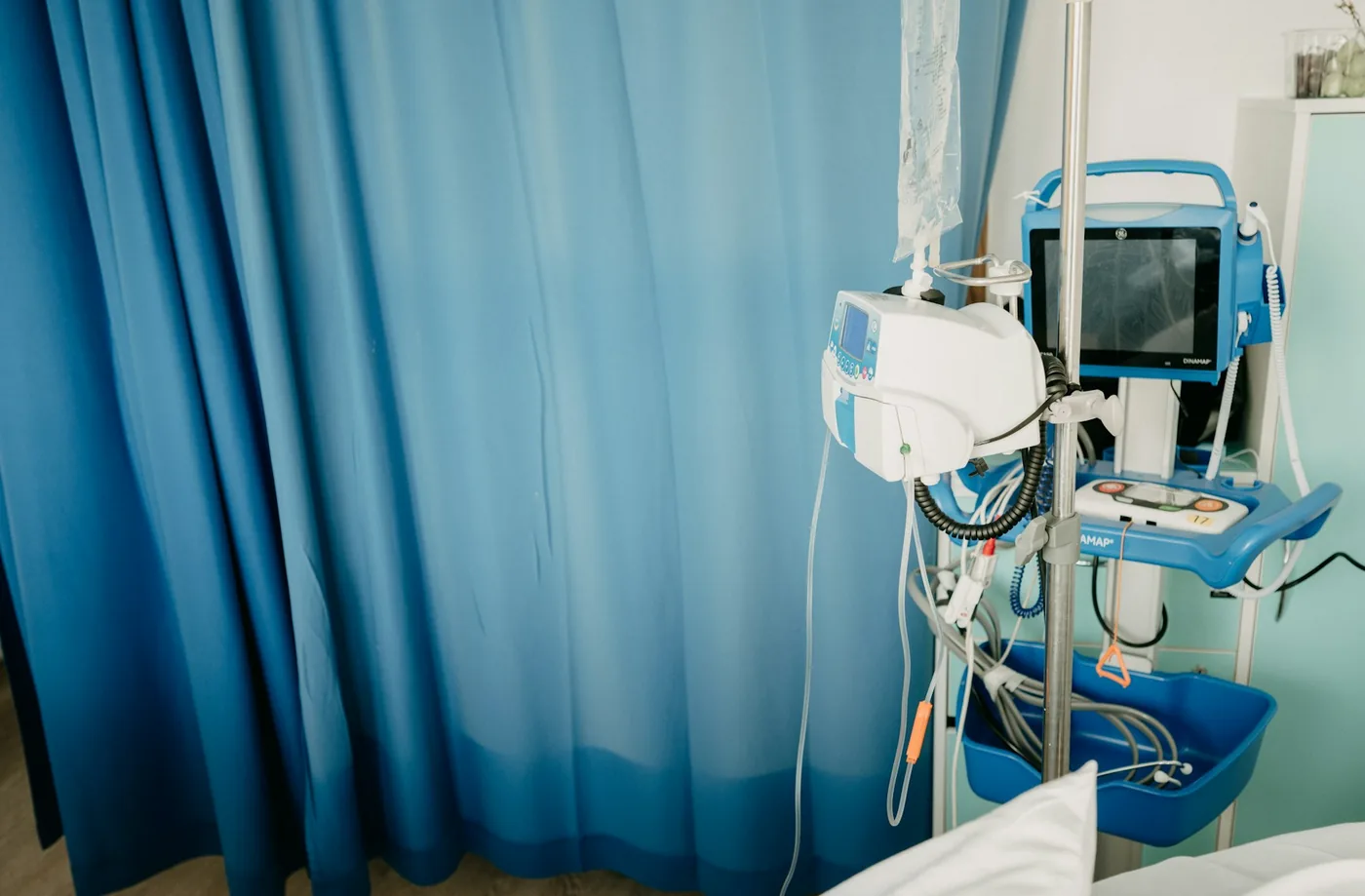 A hospital ward with privacy curtains on ceiling tracks around the beds