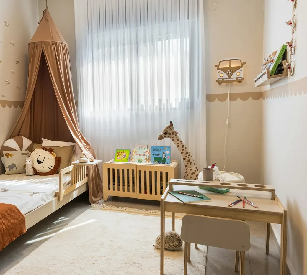 A bright child's bedroom with soft furnishings and a window