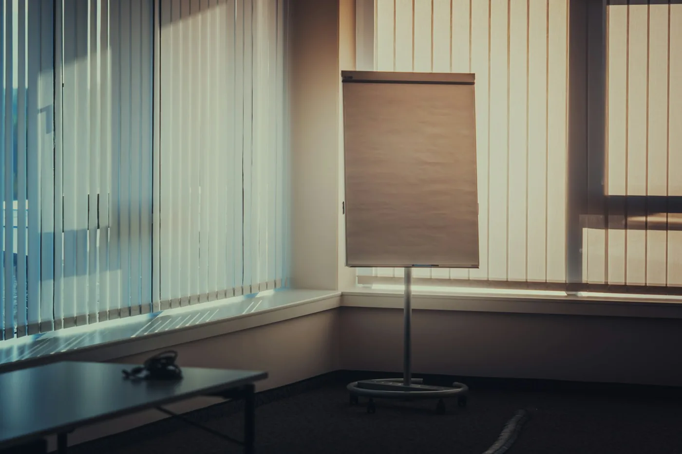 An office interior with blinds on a row of windows and workstations facing away from the glare