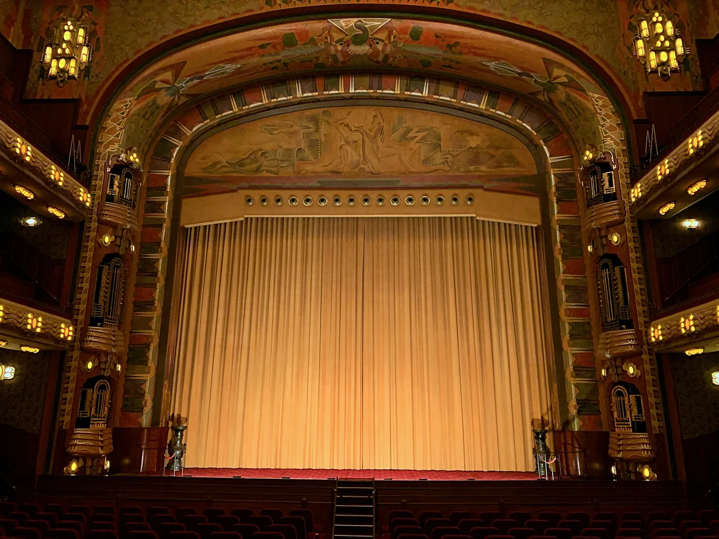 Heavy stage curtains framing a proscenium stage in an auditorium